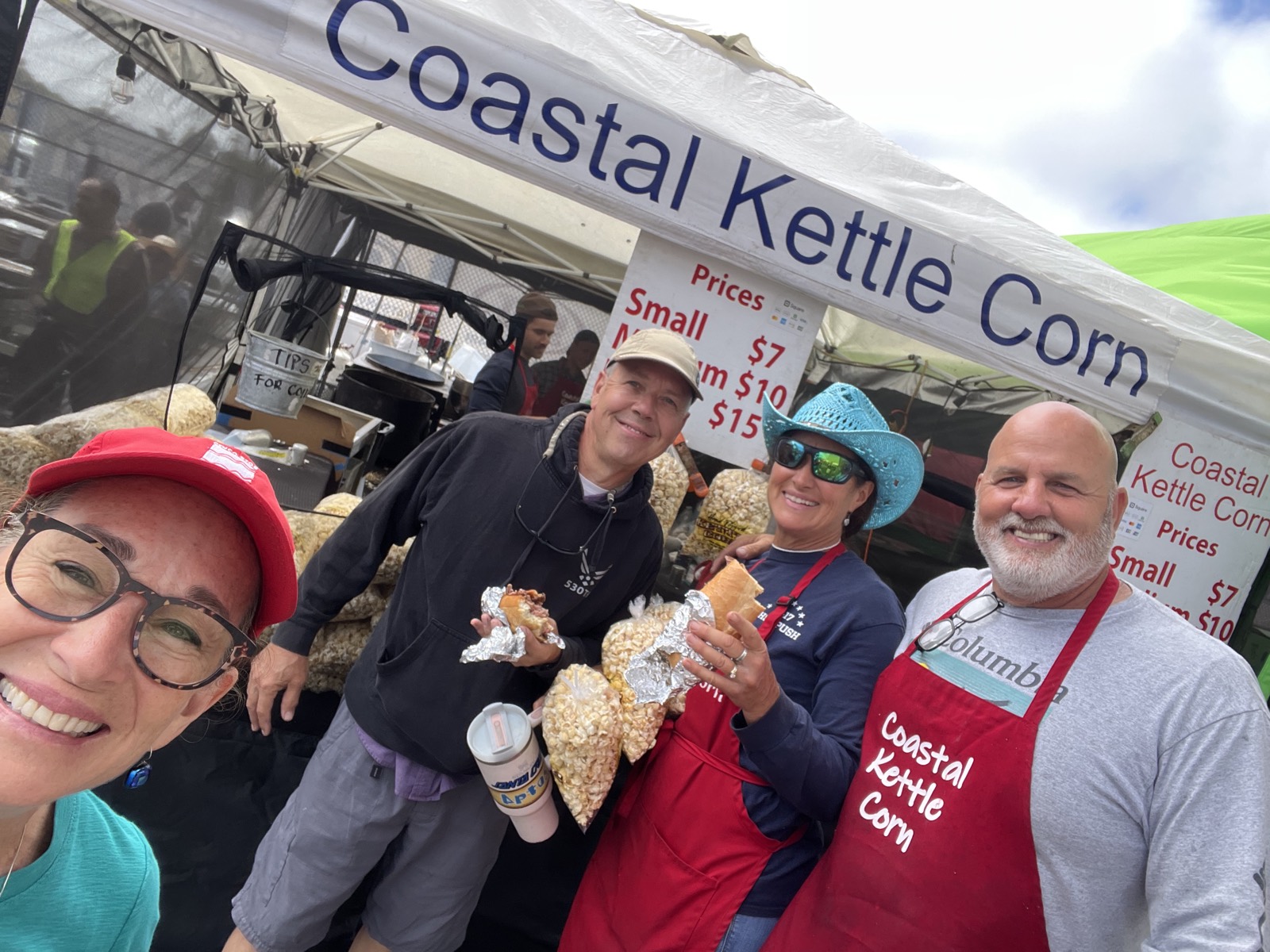 Guests gathered at the Coastal Kettle Corn booth with fresh bags of kettle corn